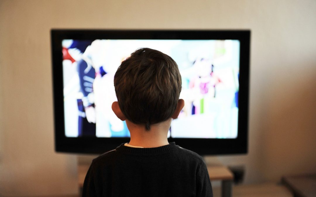 Image taken from behind a child who is watching tv
